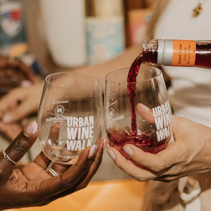 Red wine being poured into branded Urban Wine Walk glasses at The Rock