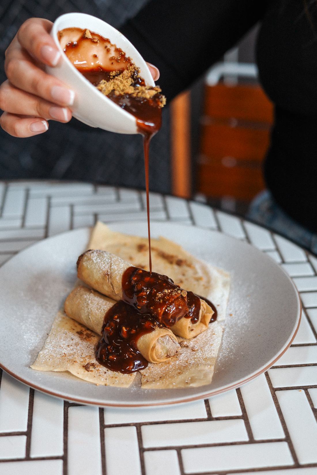 Dubai chocolate spring rolls with sauce being poured over