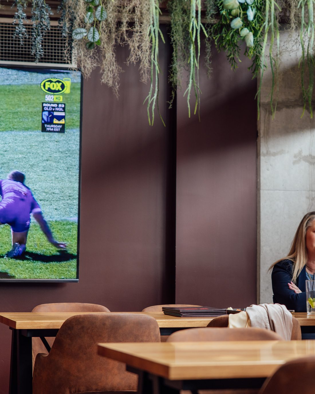 Friends at a table with the footy on the big screen at The Rock Toowoomba