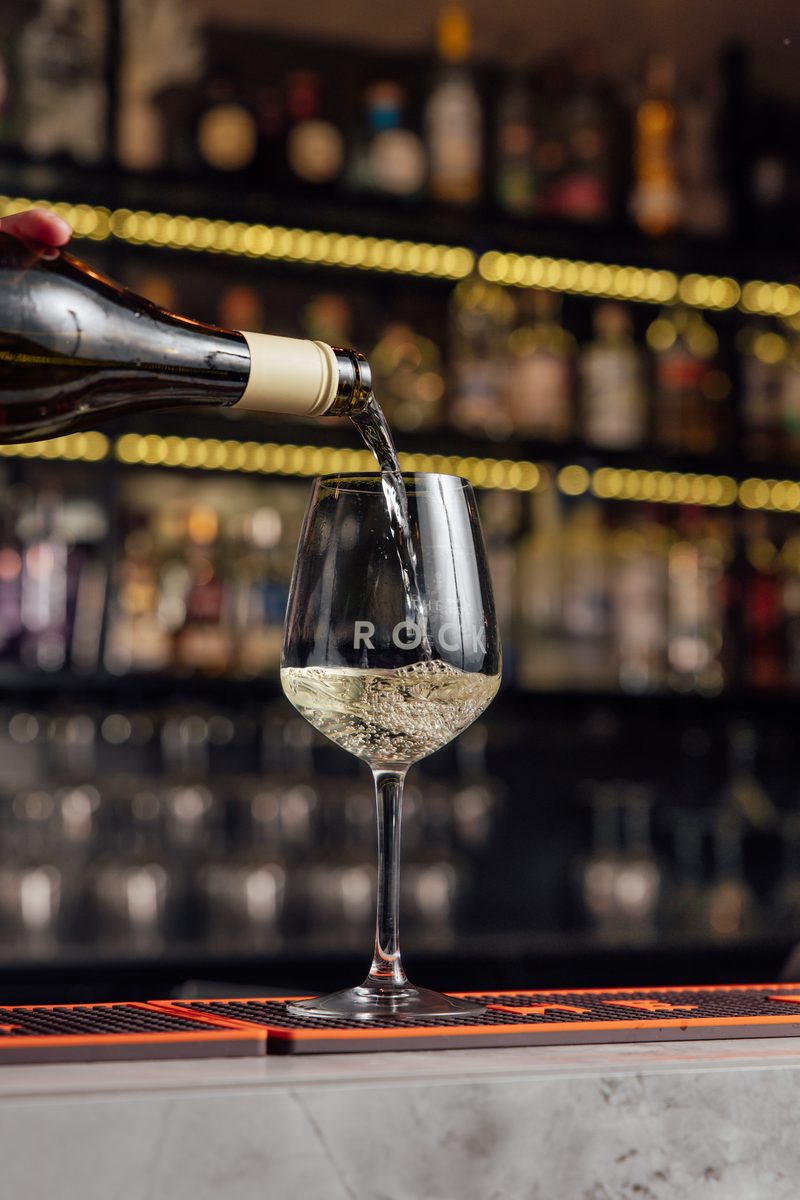 White wine poured into a branded The Rock glass at the bar